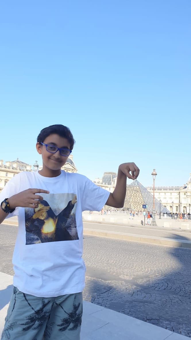 A young Naman posing in front of the Louvre pyramid