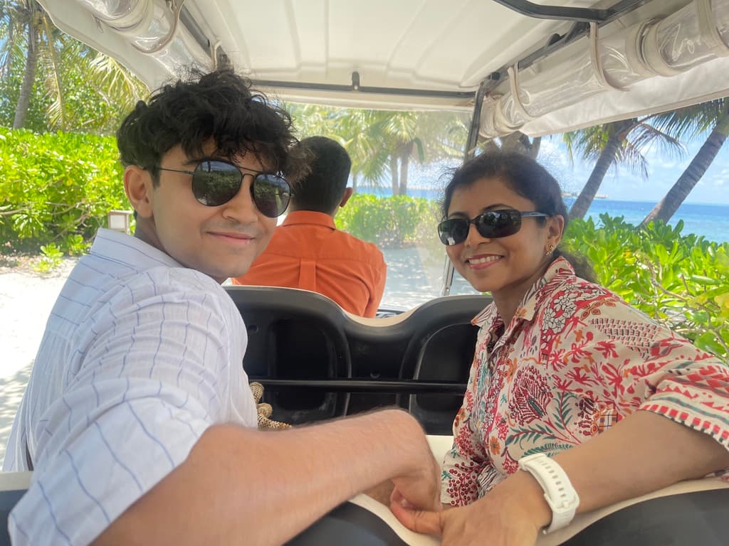 Naman and Mom in a golf cart by the beach