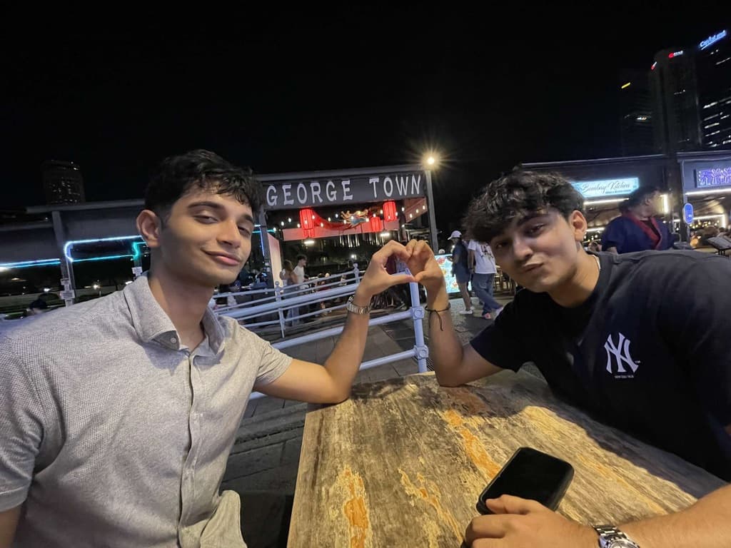 Naman and a friend at a table at night in George Town